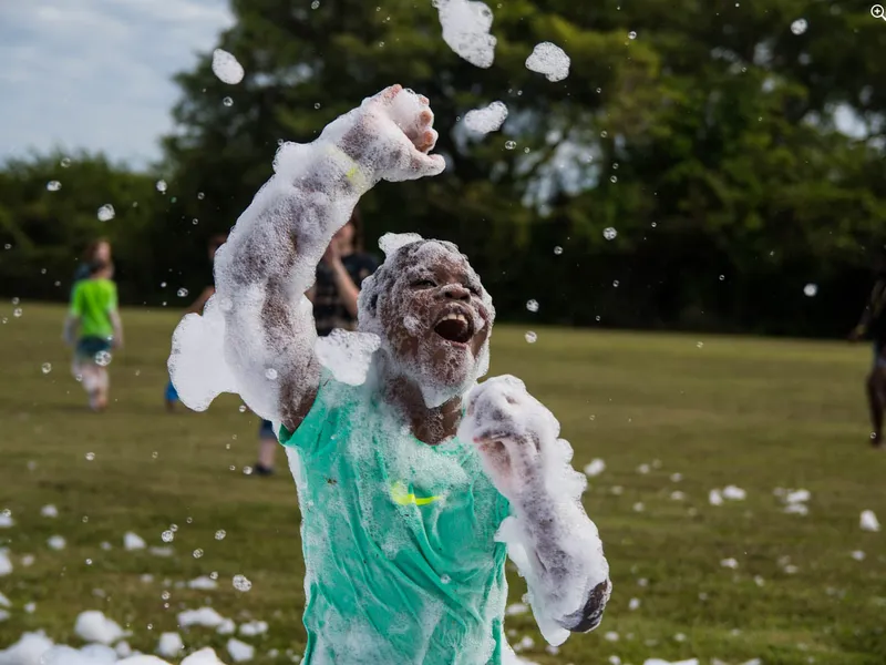 Child playing in thick foam at an outdoor foam party event in Western New York