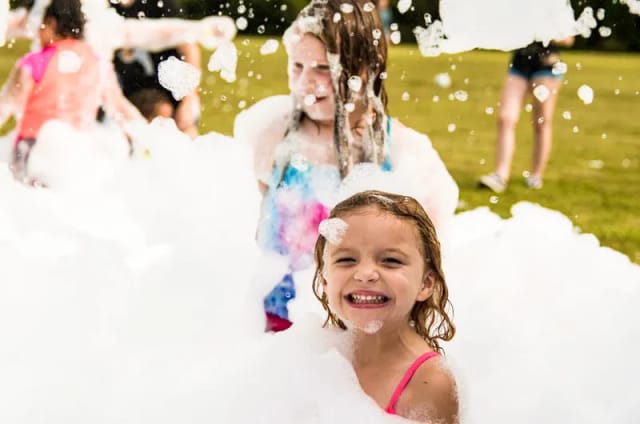 Girl smiling while covered in foam at a party