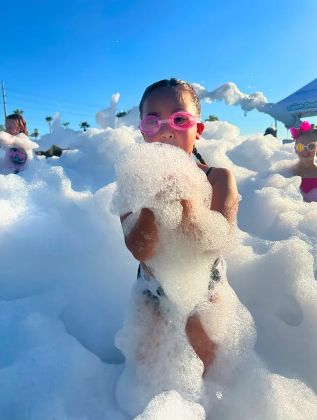 Kid wearing goggles playing in a pile of foam