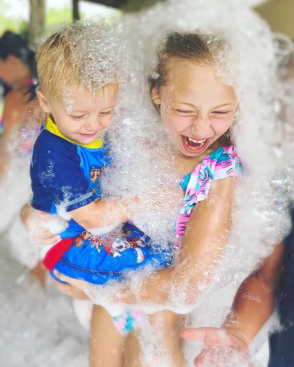 Siblings laughing together covered in foam