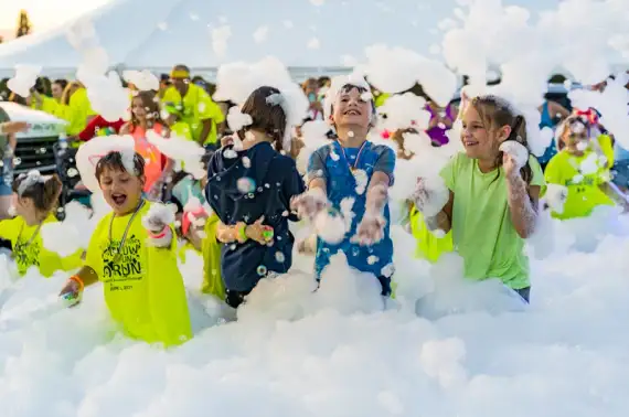 Group of kids cheering and playing at a foam party event